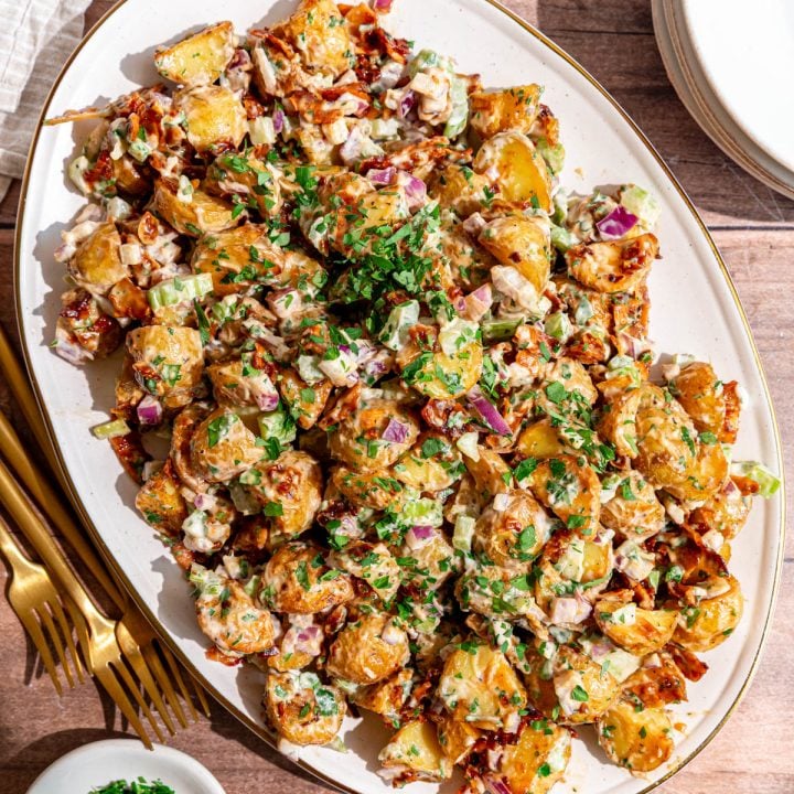 A platter of vegan roasted potato salad, garnished with extra parsley.
