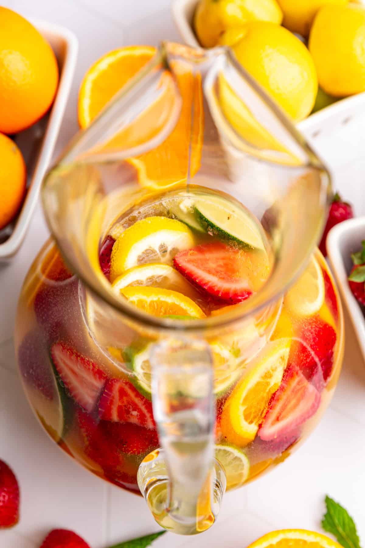 A top-down view of a pitcher of mocktail sangria, to see the fruit filling the pitcher.