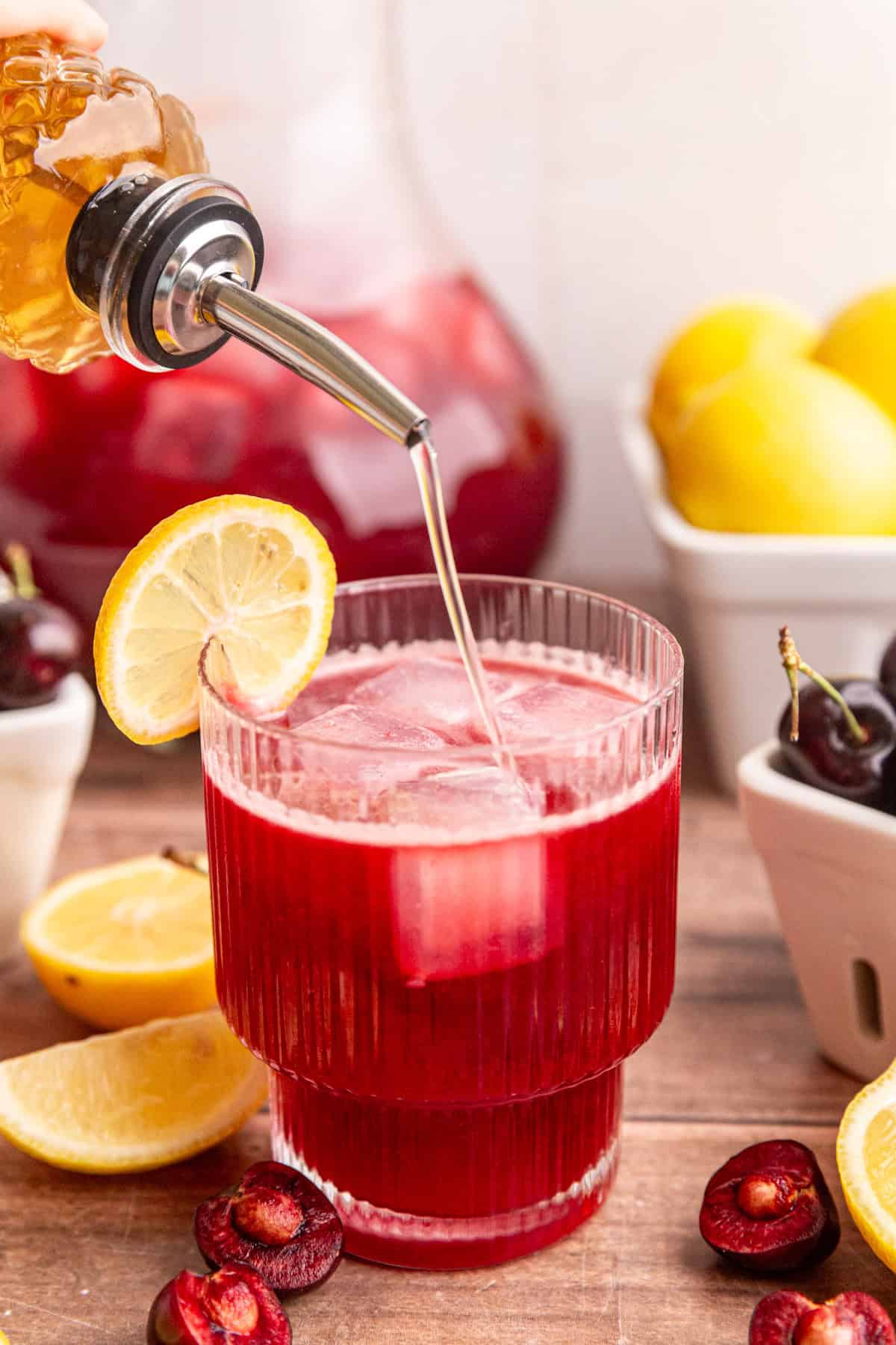Agave simple syrup being poured into cherry lemonade.