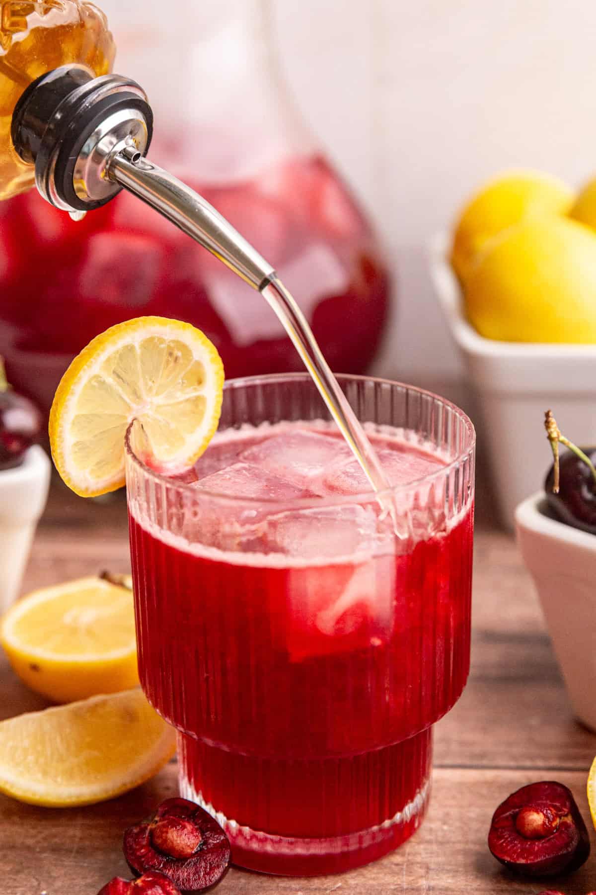 Agave simple syrup being poured into cherry lemonade.