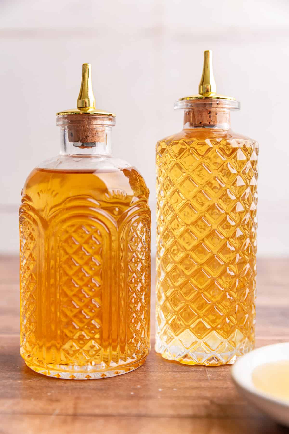 A two bottles of agave simple syrup on a table.