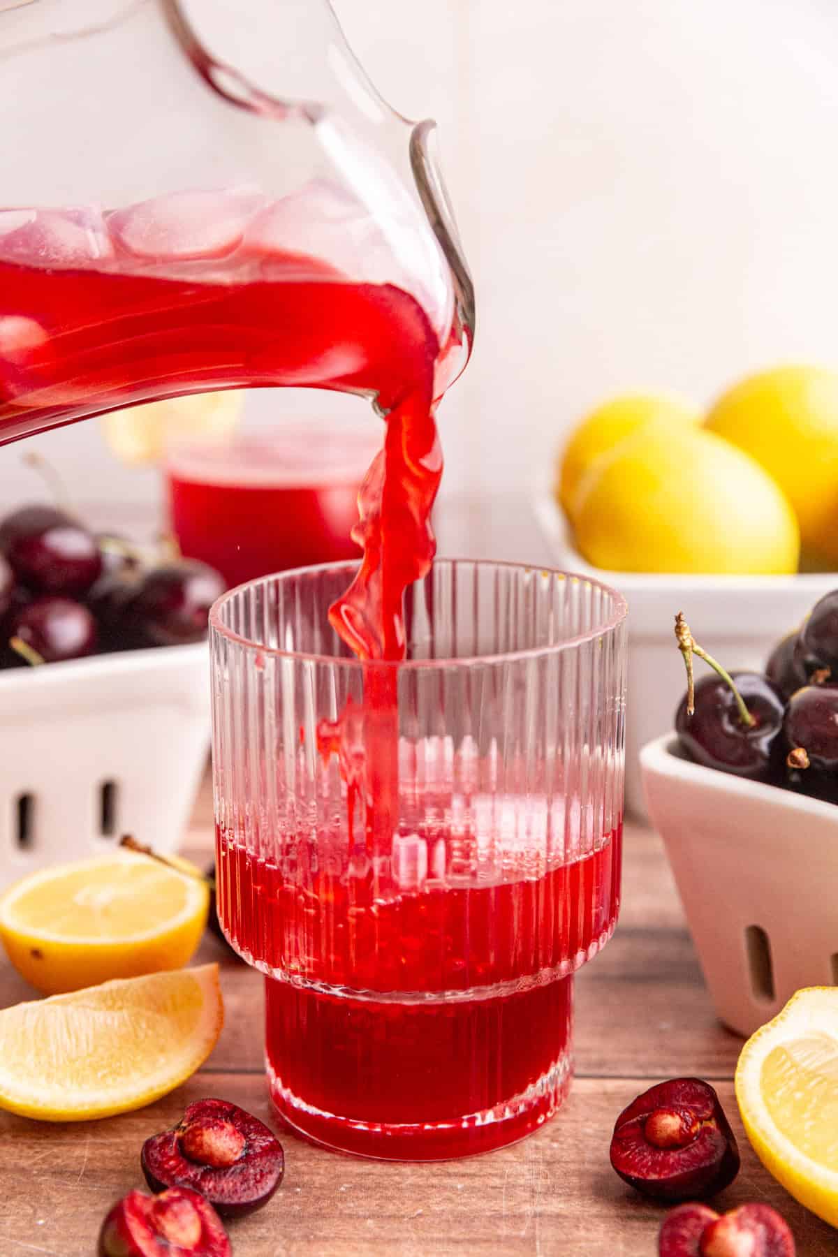 Cherry lemonade being poured into a glass.