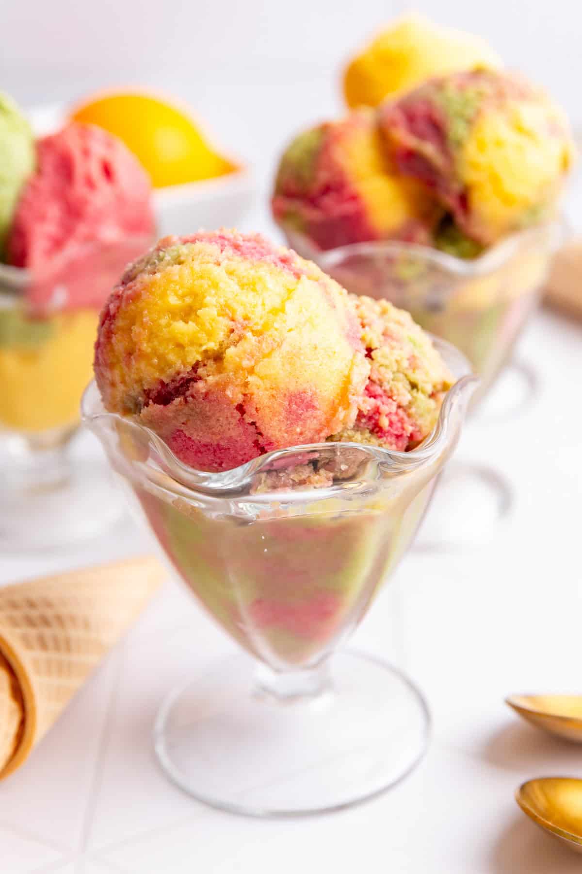 No churn dairy free orange, raspberry, and lime sherbet, mixed together in an ice cream glass.