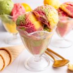 No churn dairy free orange, raspberry, and lime sherbet, mixed together in an ice cream glass.