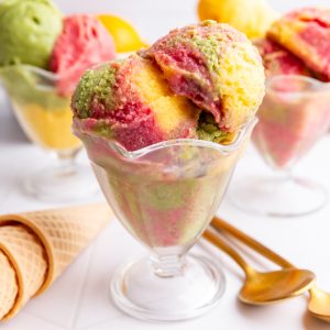 No churn dairy free orange, raspberry, and lime sherbet, mixed together in an ice cream glass.