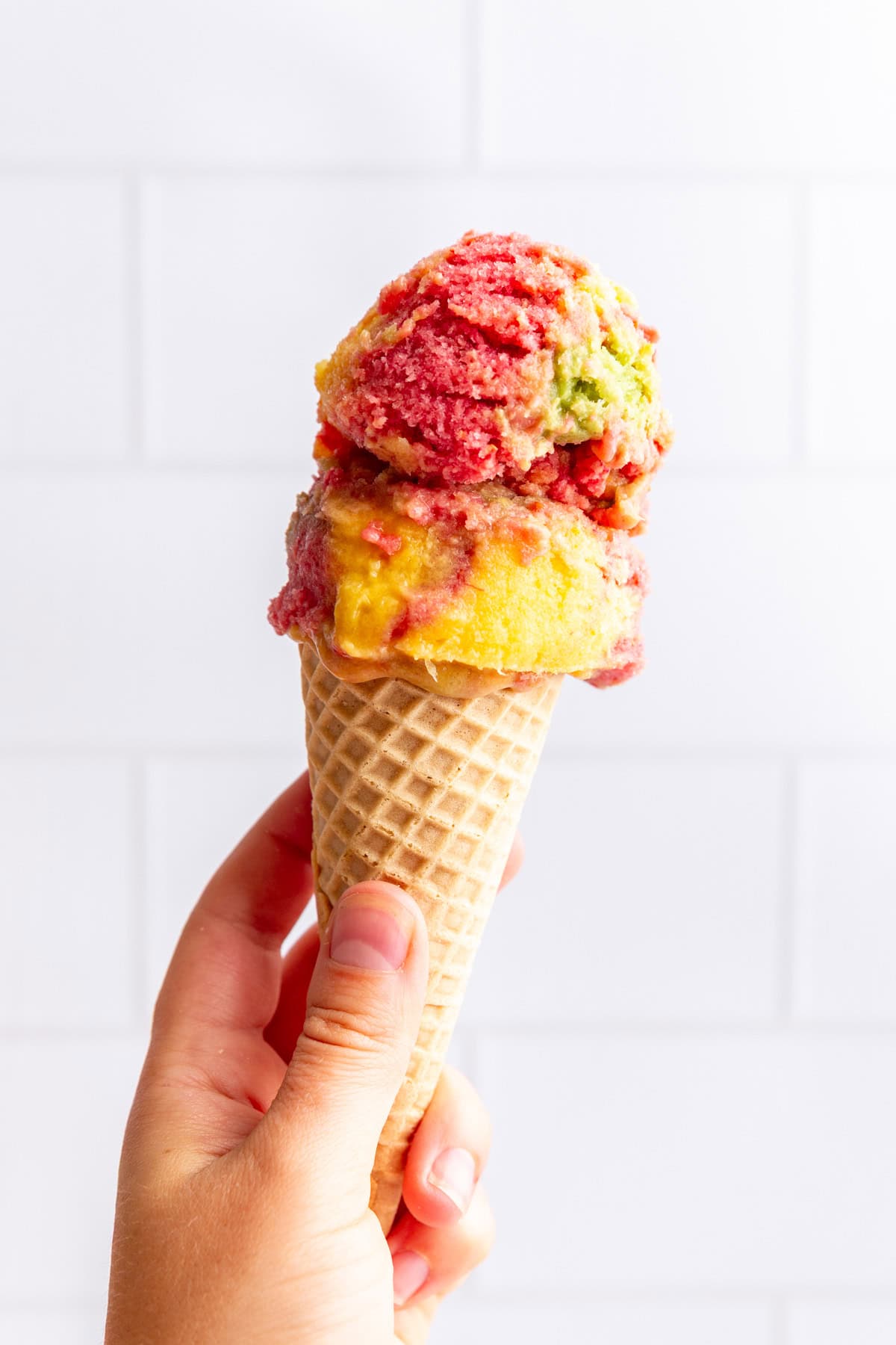 A hand holding a cone of vegan sherbet.