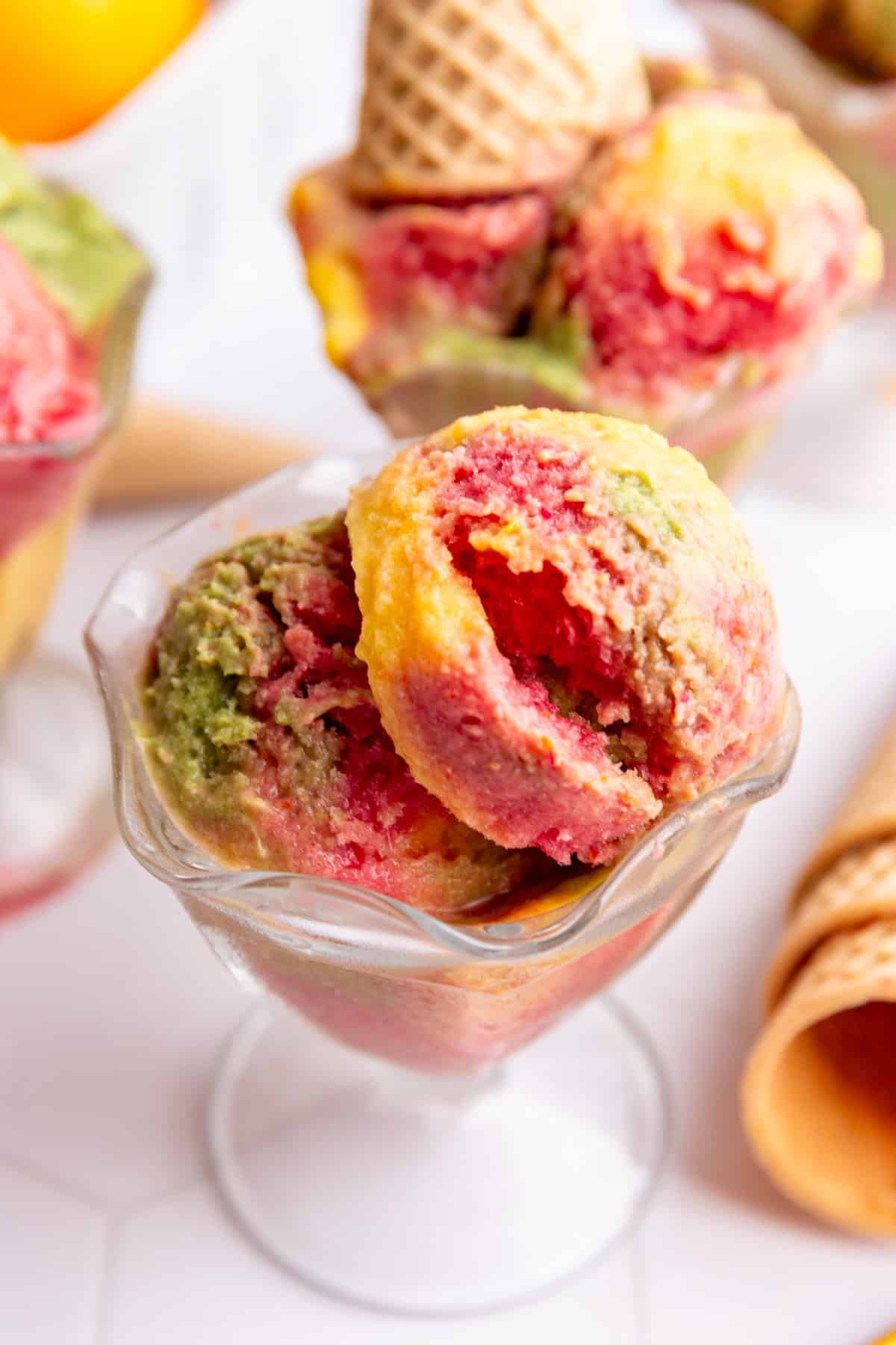 No churn dairy free orange, raspberry, and lime sherbet, mixed together in an ice cream glass.