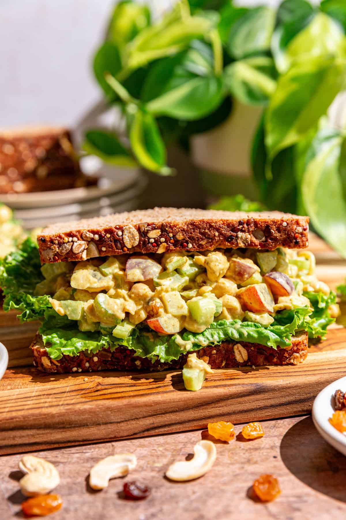A curry chickpea salad sandwich on a cutting board.