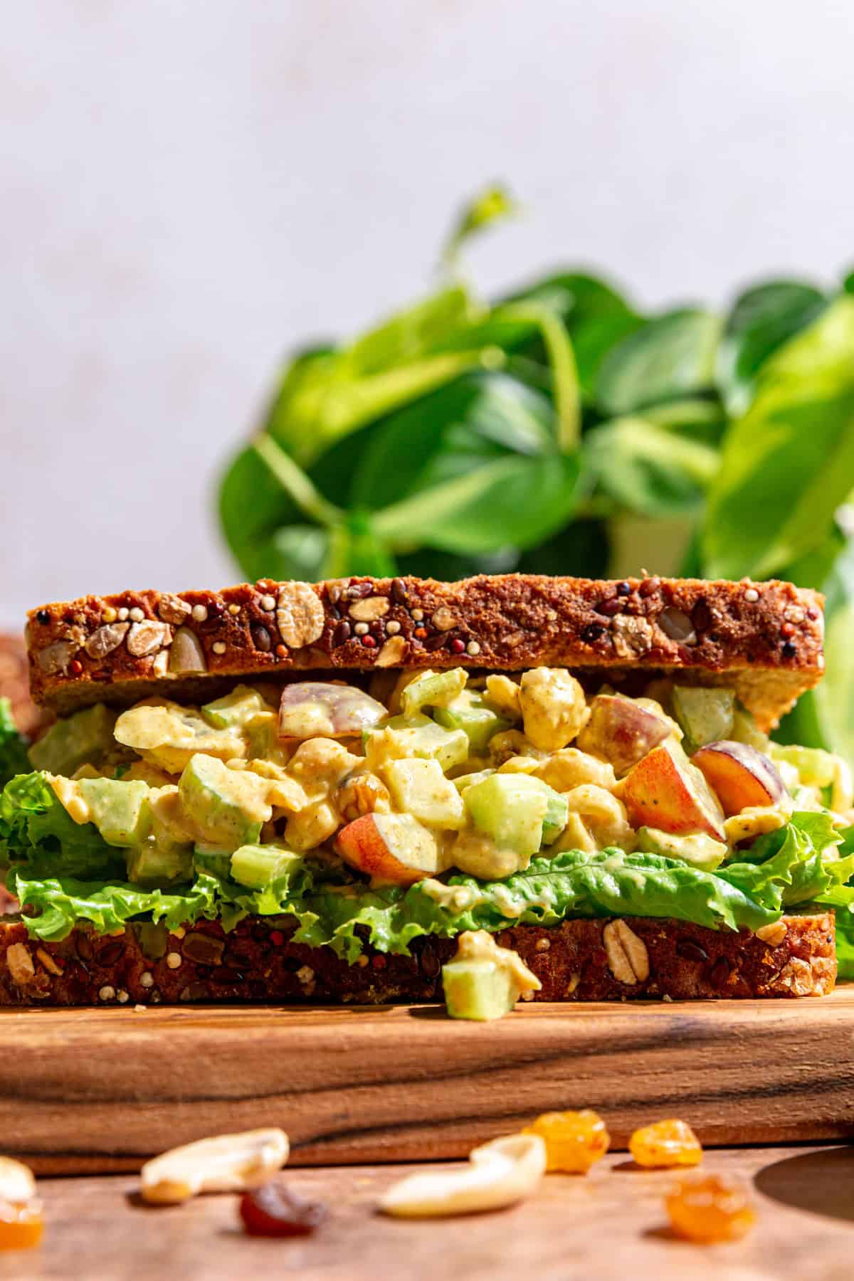 A curry chickpea salad sandwich on a cutting board.