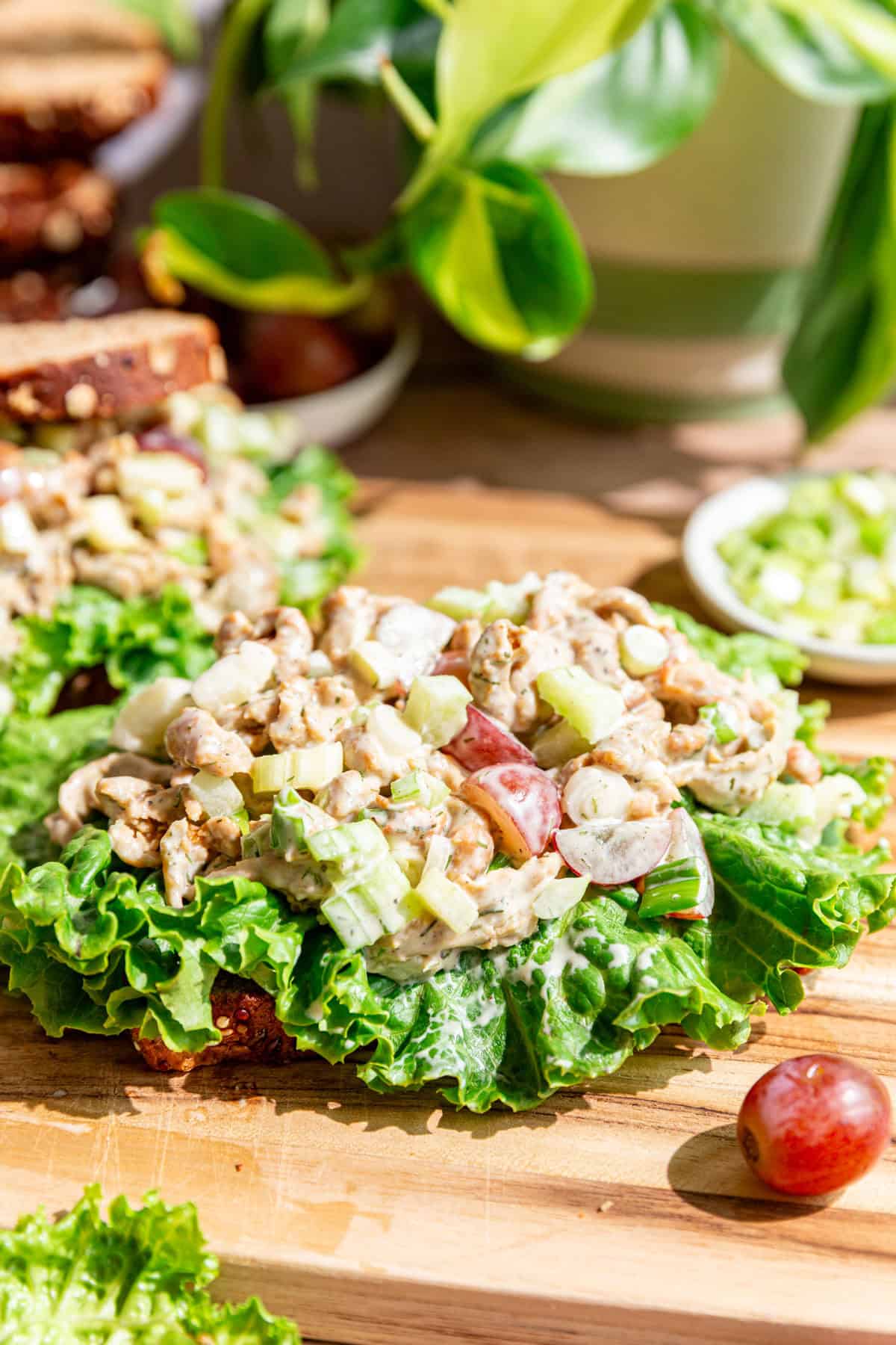 An open faced vegan Protein Chicken Salad sandwich on a cutting board.