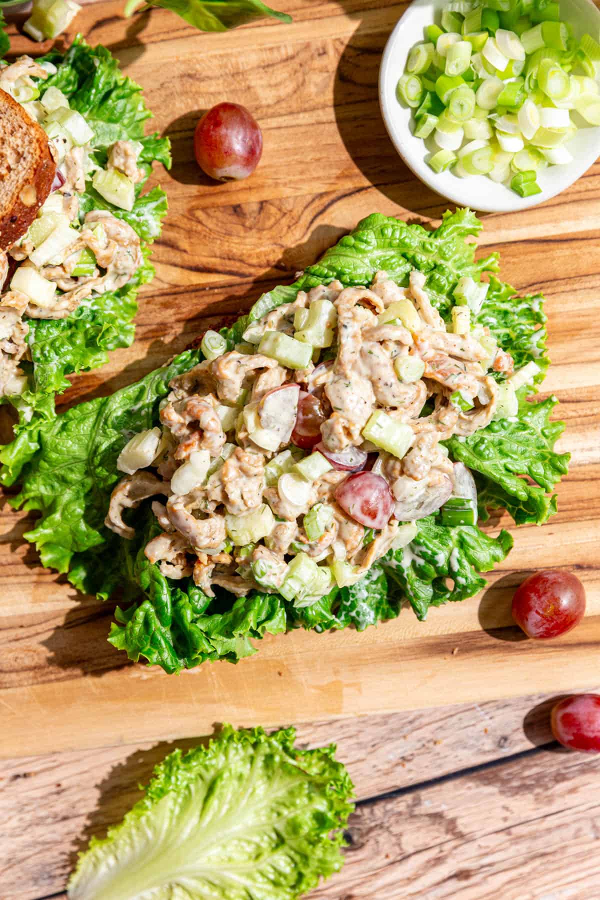 An open faced vegan Protein Chicken Salad sandwich on a cutting board.