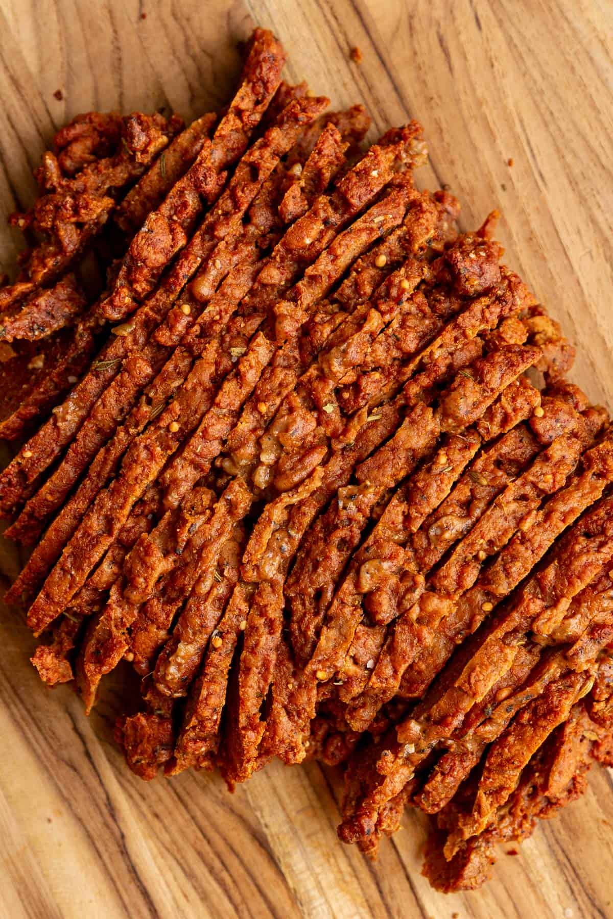 A bath of seitan pastrami sliced on a cutting board.
