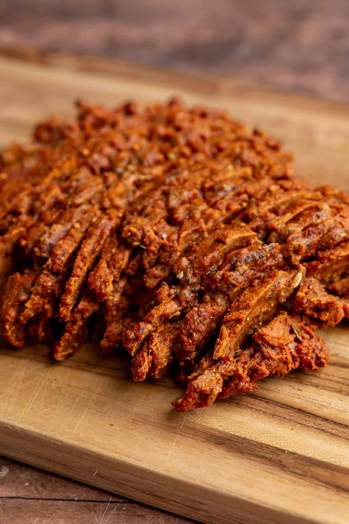 A bath of seitan pastrami sliced on a cutting board.