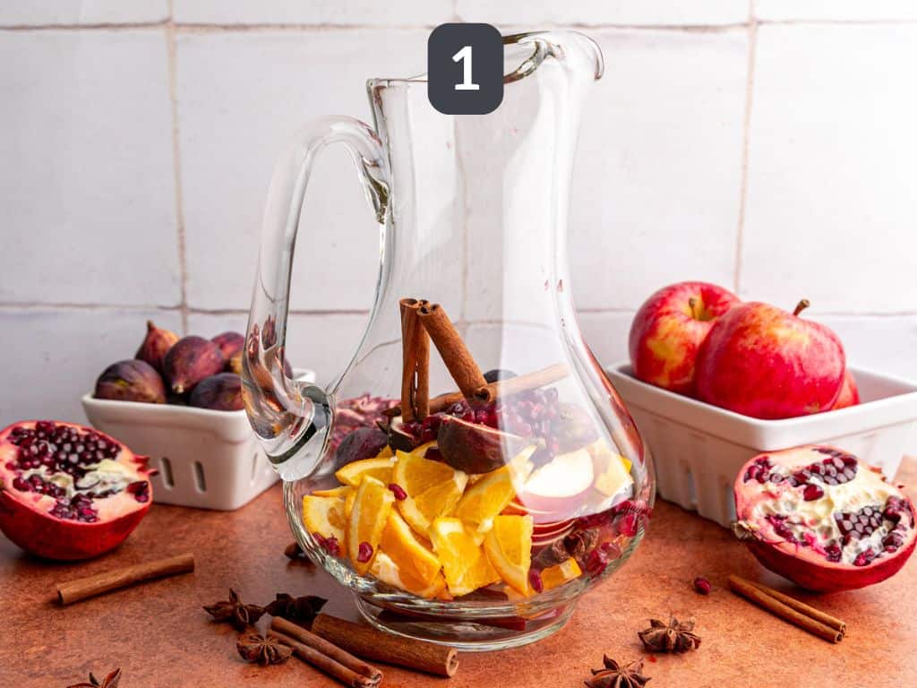 Apple cider sangria mocktail step 1 - add the fruit to the pitcher.
