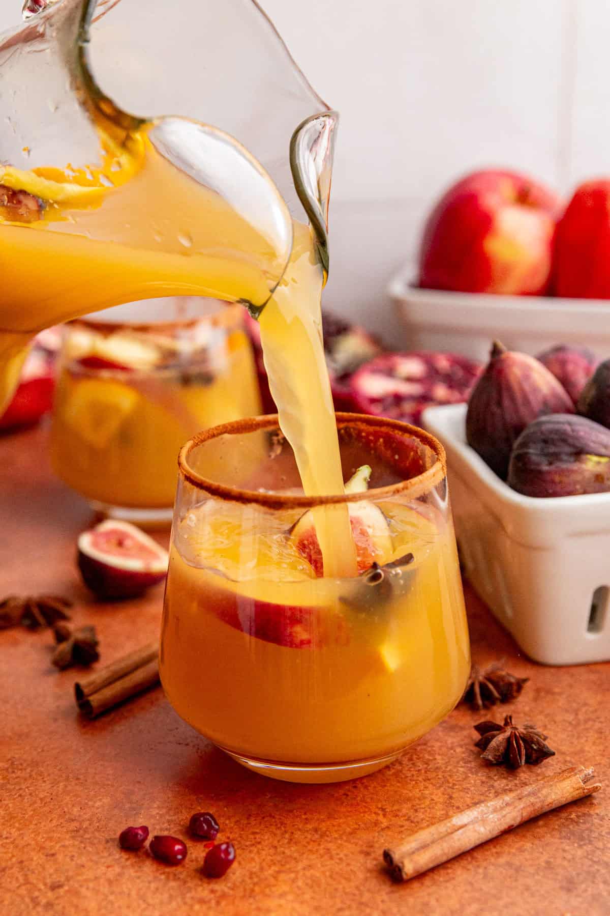 A glass of Fall apple cider sangria mocktail being poured.