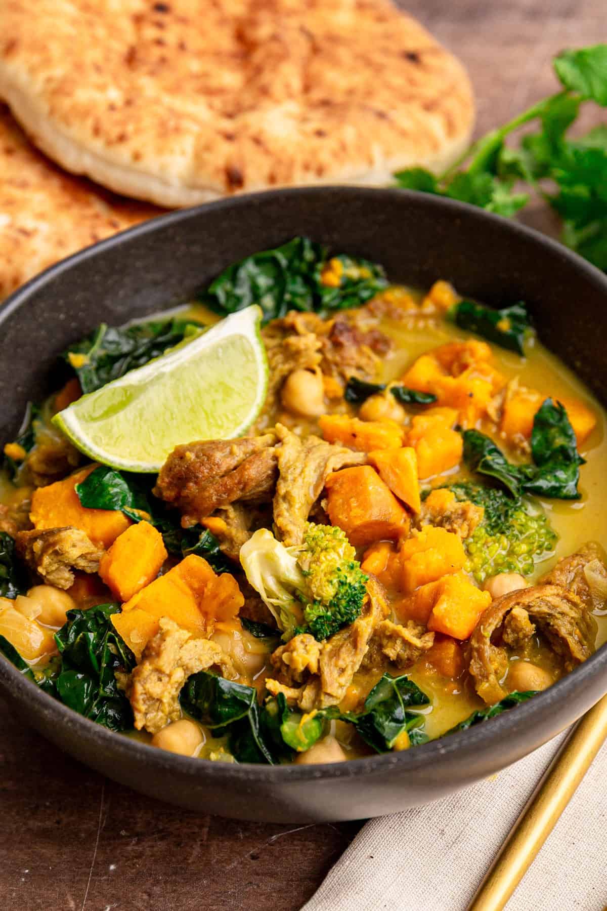 A bowl of seitan curry served with a lime wedge.