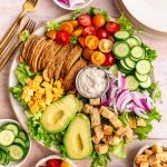 A platter of Vegan Chef Salad surrounded by small bowls of salad ingredients.