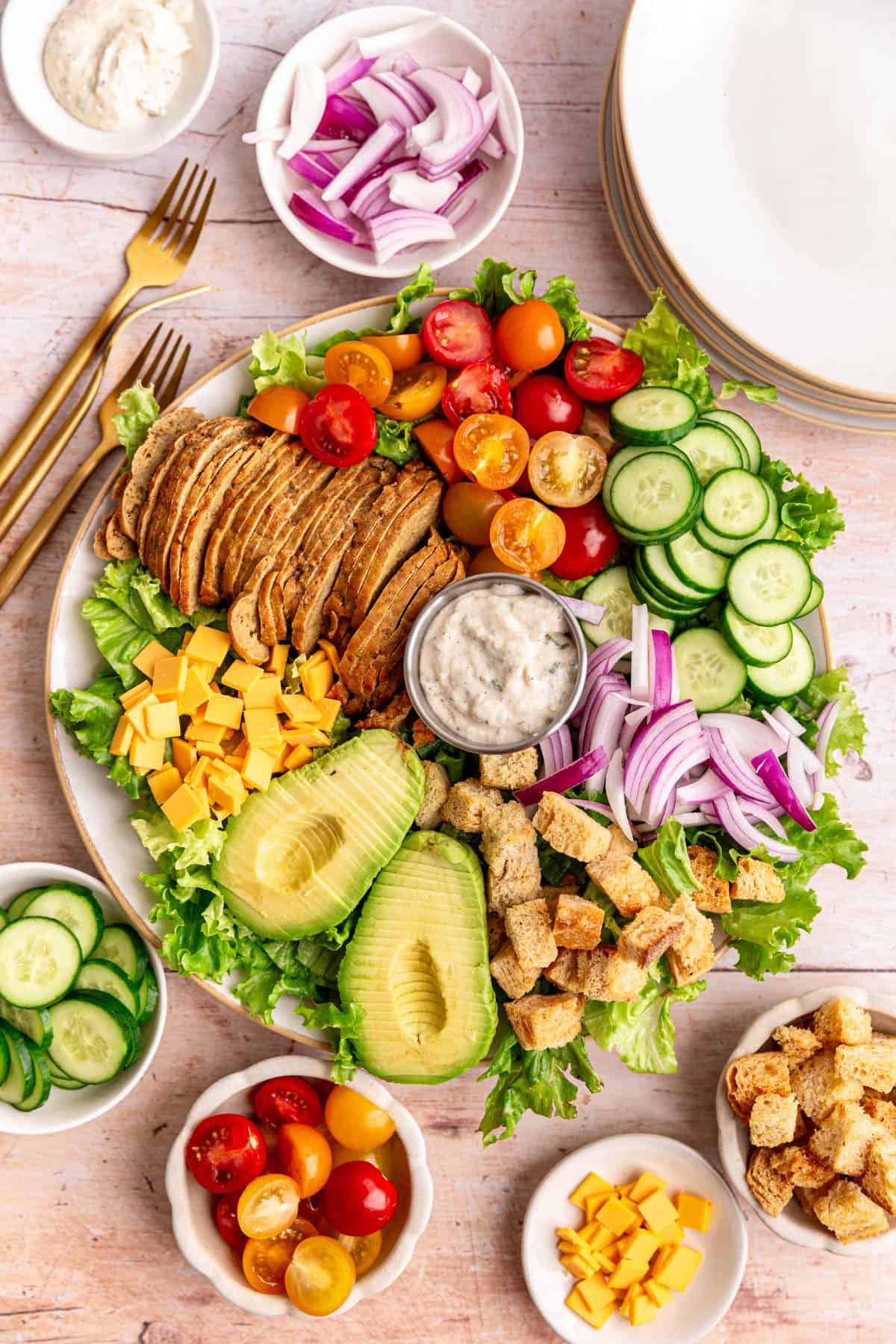 A platter of Vegan Chef Salad surrounded by small bowls of salad ingredients.