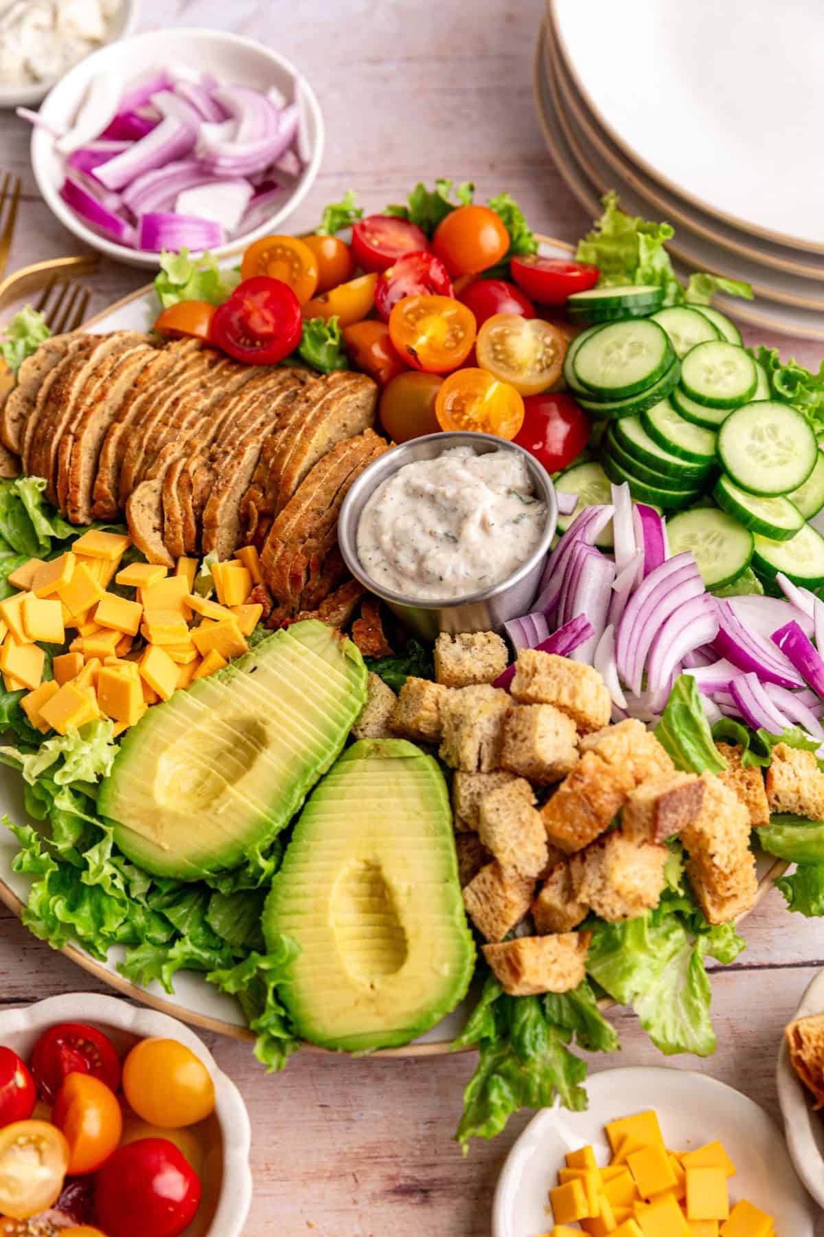 A platter of Vegan Chef Salad surrounded by small bowls of salad ingredients.
