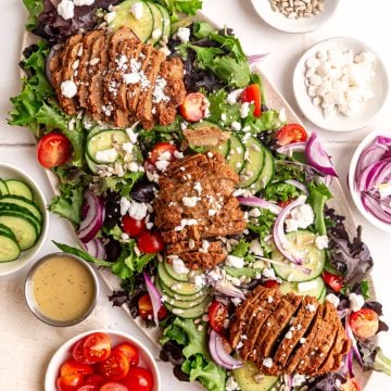 A platter of vegan steak salad, with three seitan steaks.