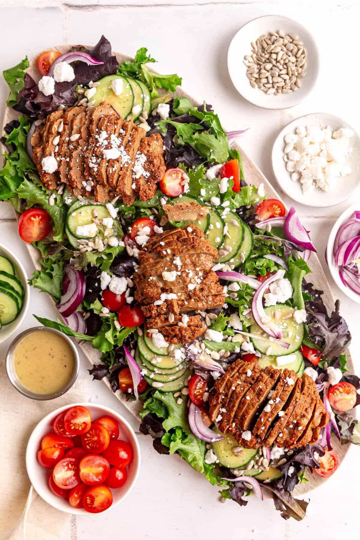 A platter of vegan steak salad, with three seitan steaks.