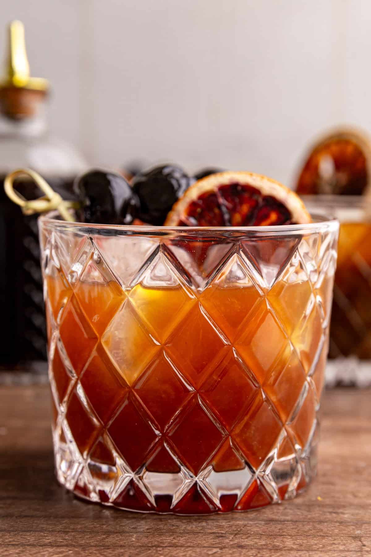 A whiskey sour mocktail garnished with a dried blood orange and cocktail cherries.
