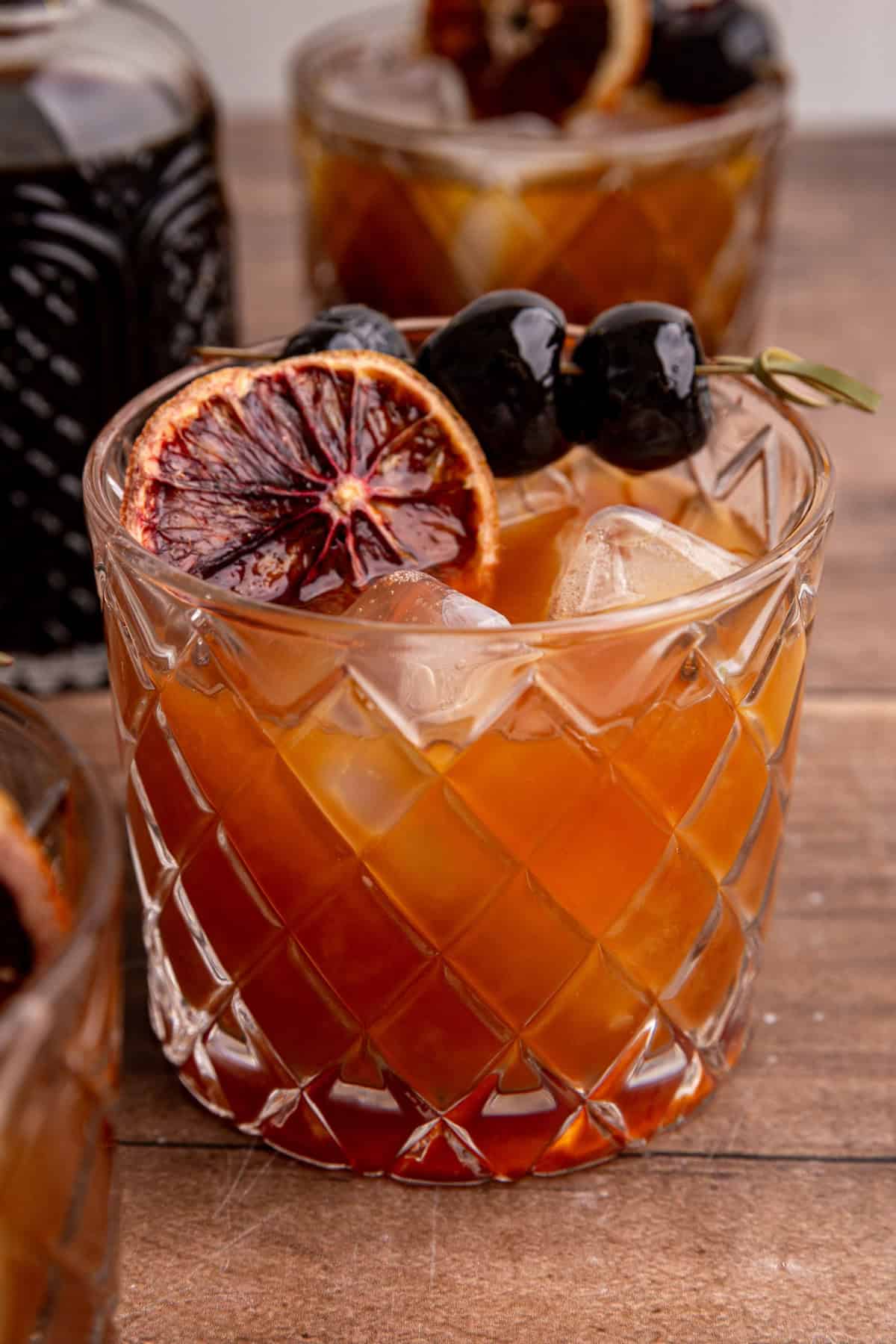 A whiskey sour mocktail garnished with a dried blood orange and cocktail cherries.