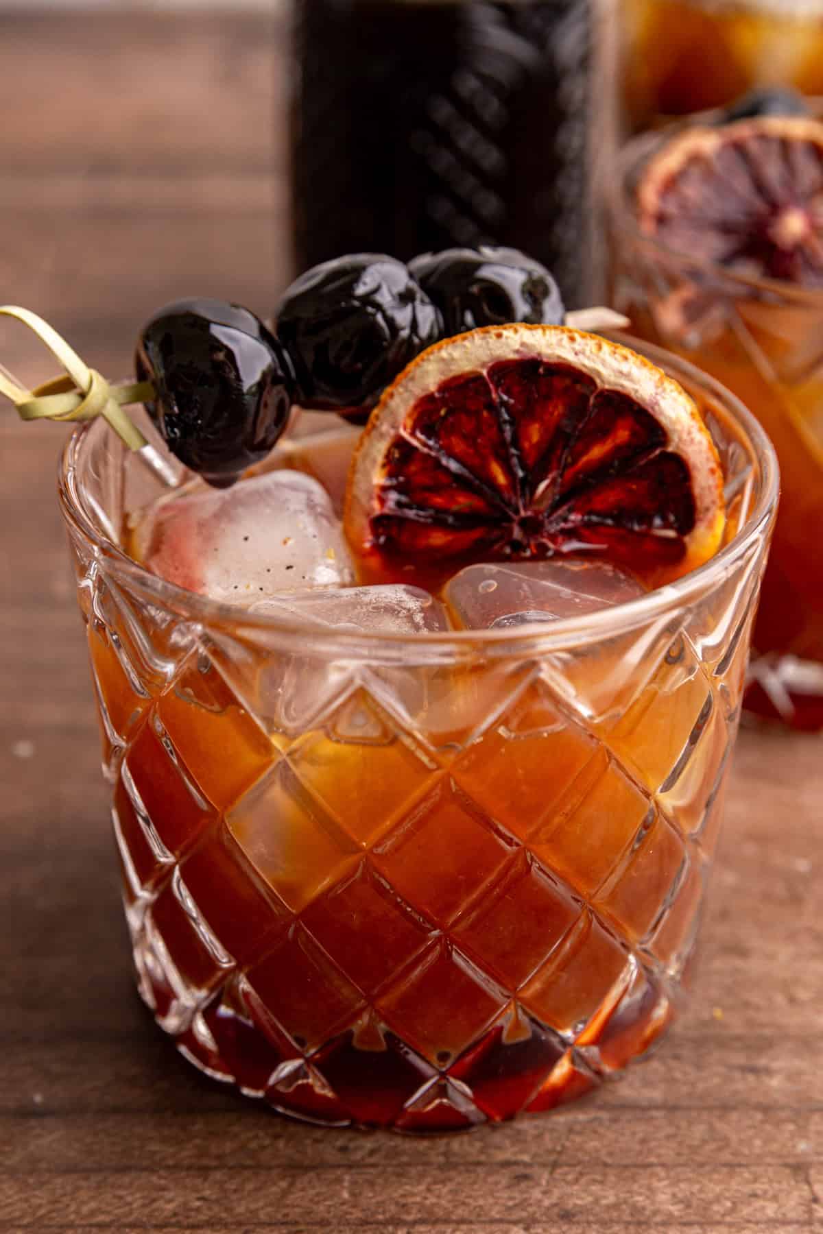 A whiskey sour mocktail garnished with a dried blood orange and cocktail cherries.