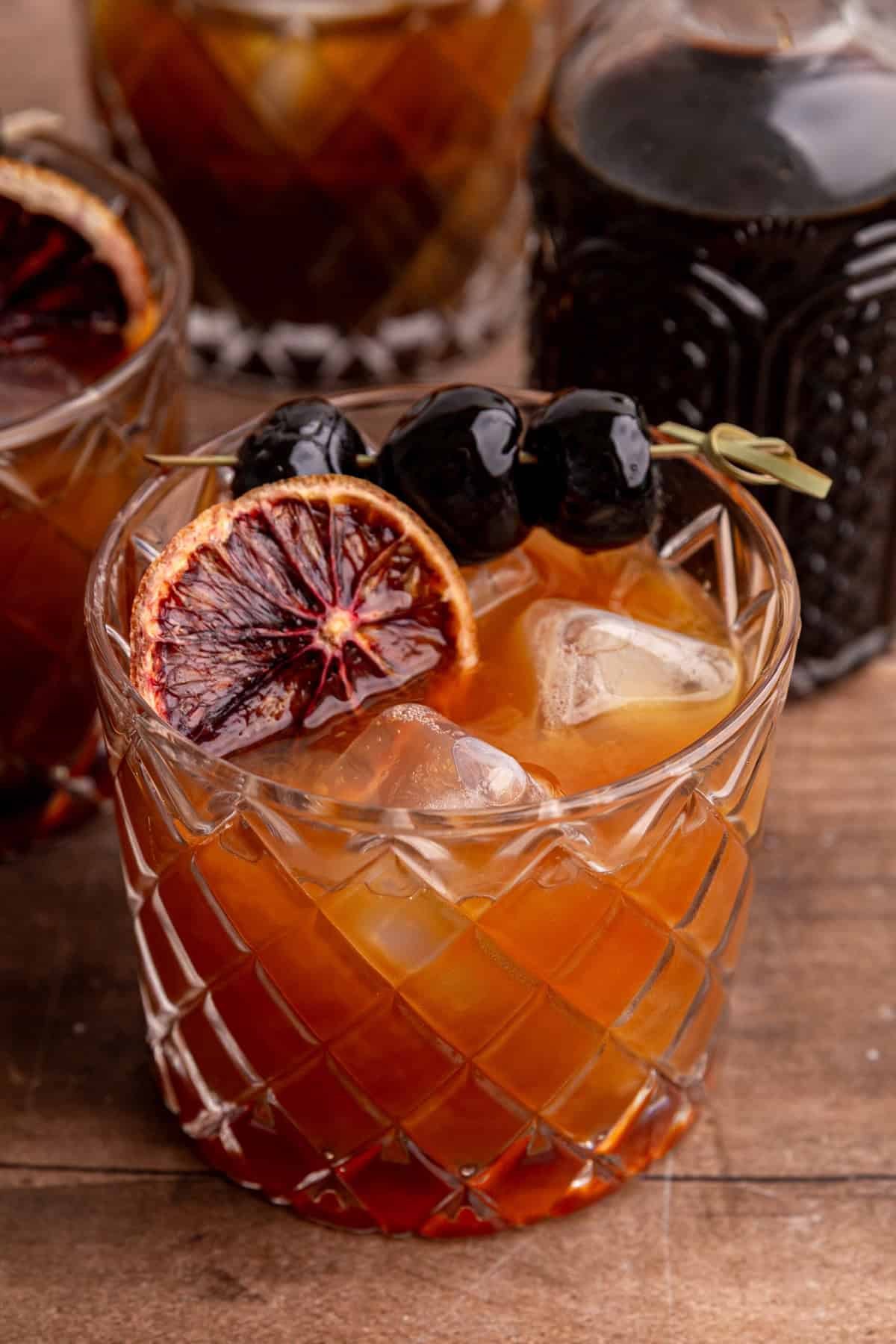 A whiskey sour mocktail garnished with a dried blood orange and cocktail cherries.
