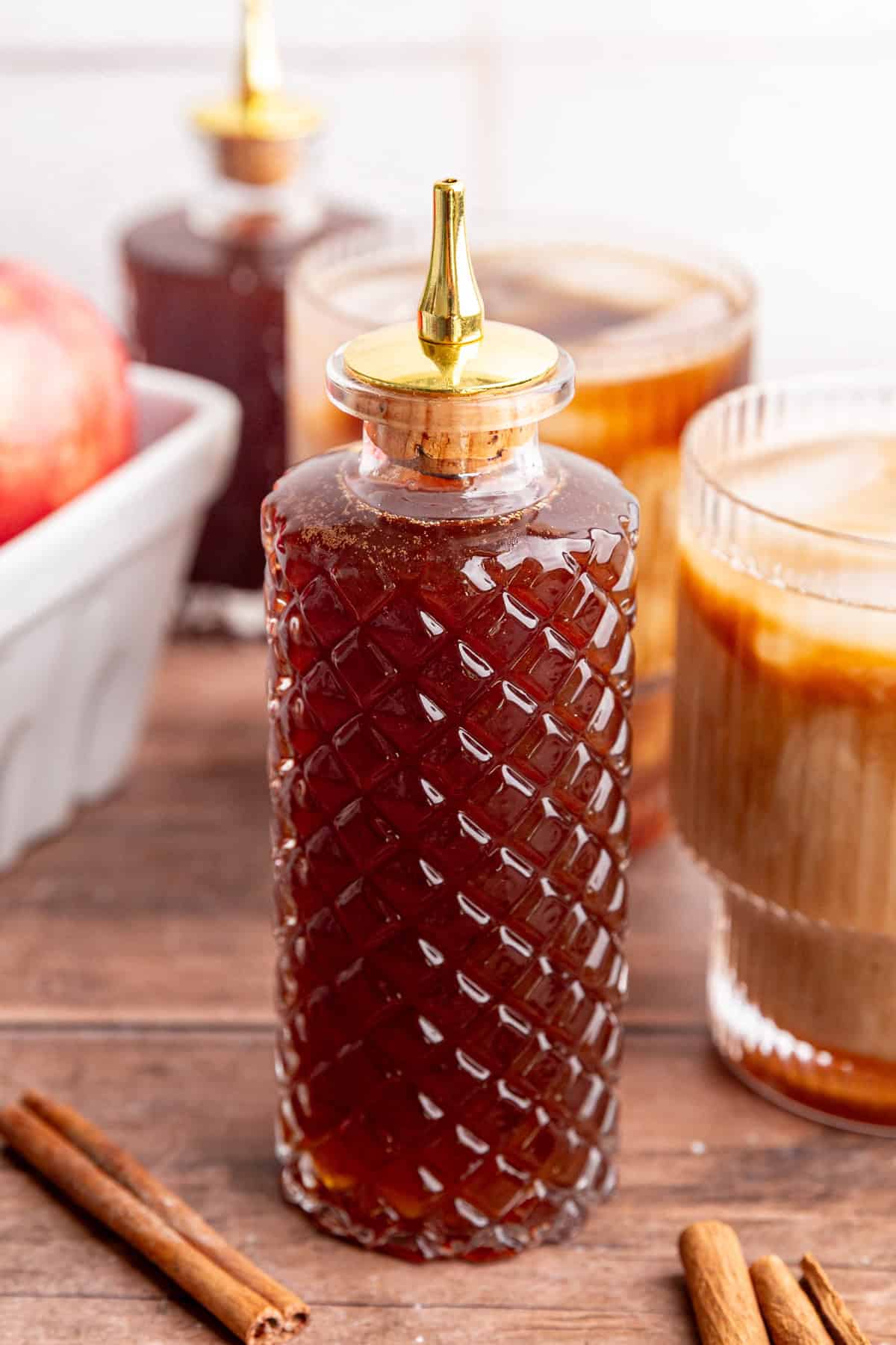 An iced apple crisp latte and a bottle of brown sugar apple crisp syrup.