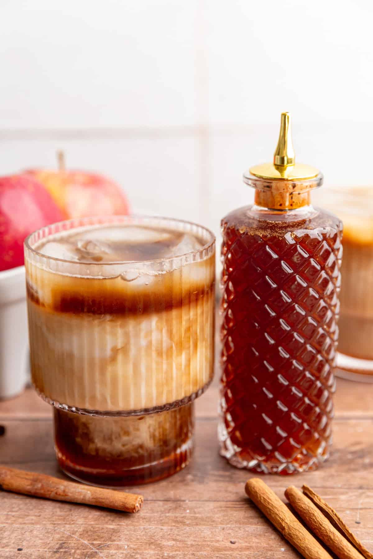 An iced apple crisp latte and a bottle of brown sugar apple crisp syrup.