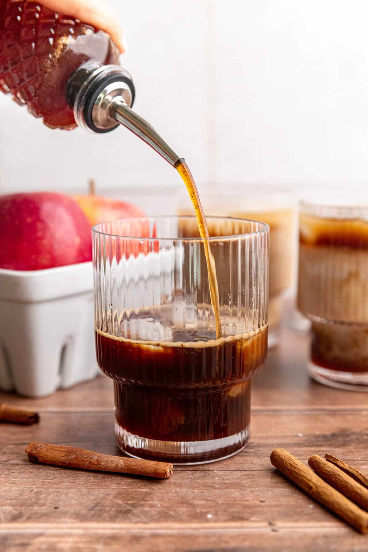 Brown sugar apple crisp syrup being poured into an iced apple crisp latte.