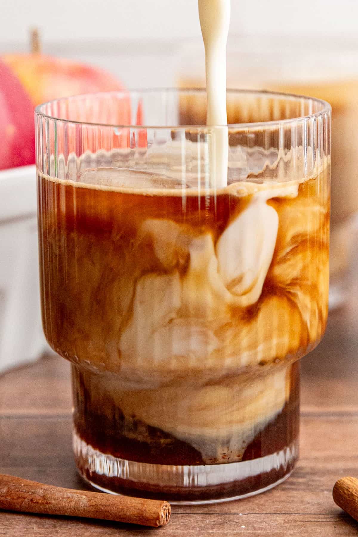 Milk being poured into an iced apple crisp latte.