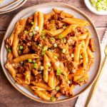 A plate of vegan chorizo pasta, garnished with fresh scallions.