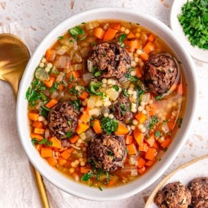 A bowl of vegan Italian wedding soup, garnished with fresh parssley.