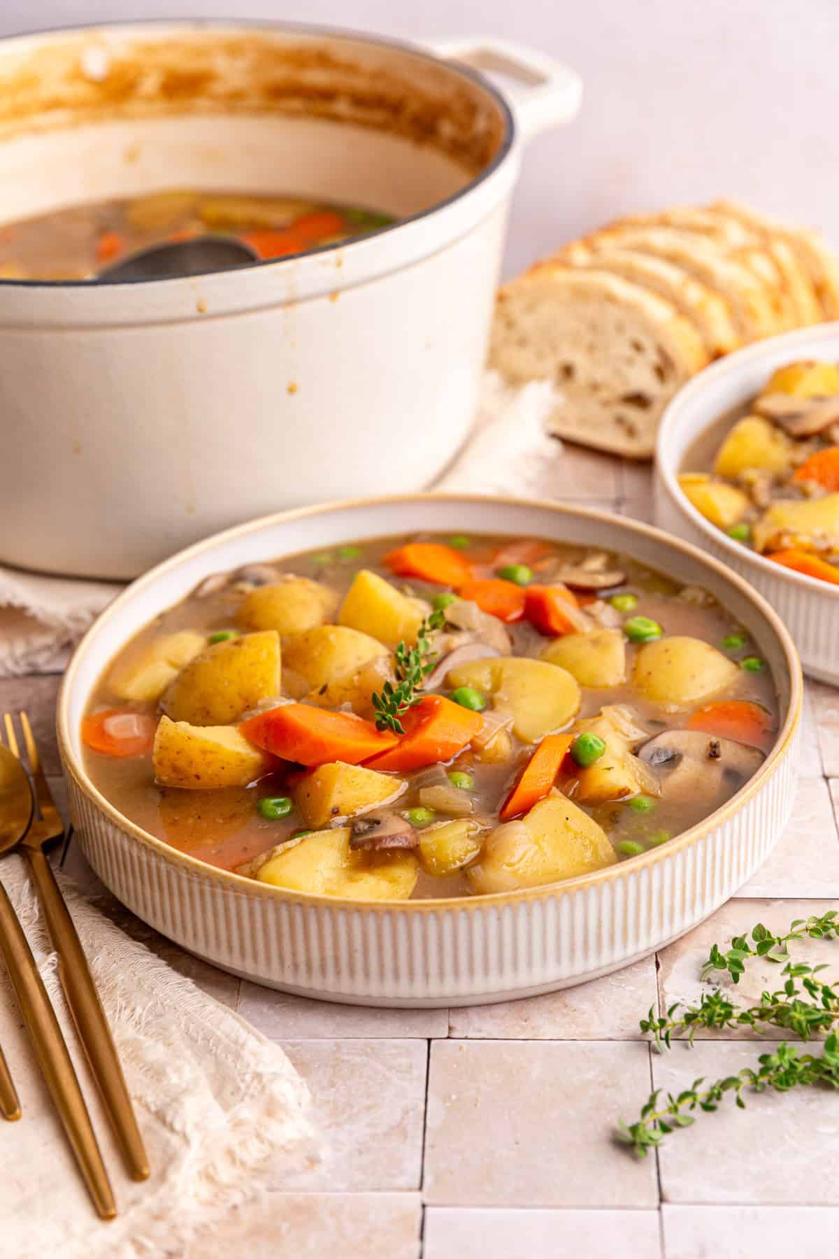 A bowl of potato stew next to the pot of stew.