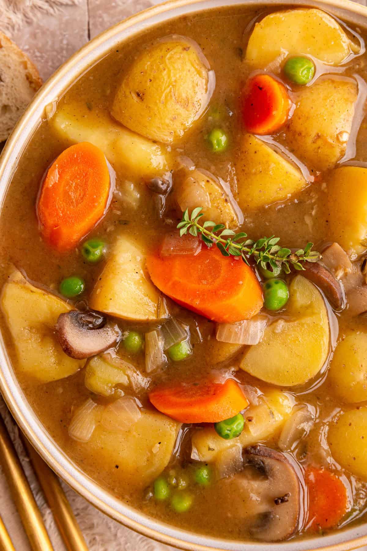 A bowl of vegan potato stew with a garnish of fresh thyme.