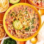 A bowl of Vegan Southwest Soup, topped with avocado, cheese, tortilla strips, and cilantro.