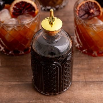 A jar of coconut sugar simple syrup, with a few whiskey sour mocktails.