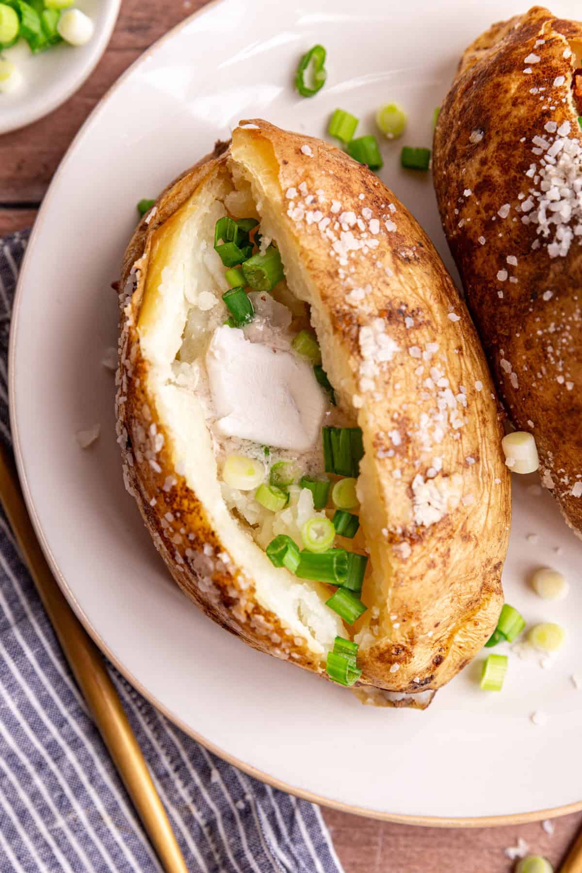 A baked potato with vegan butter and scallions.