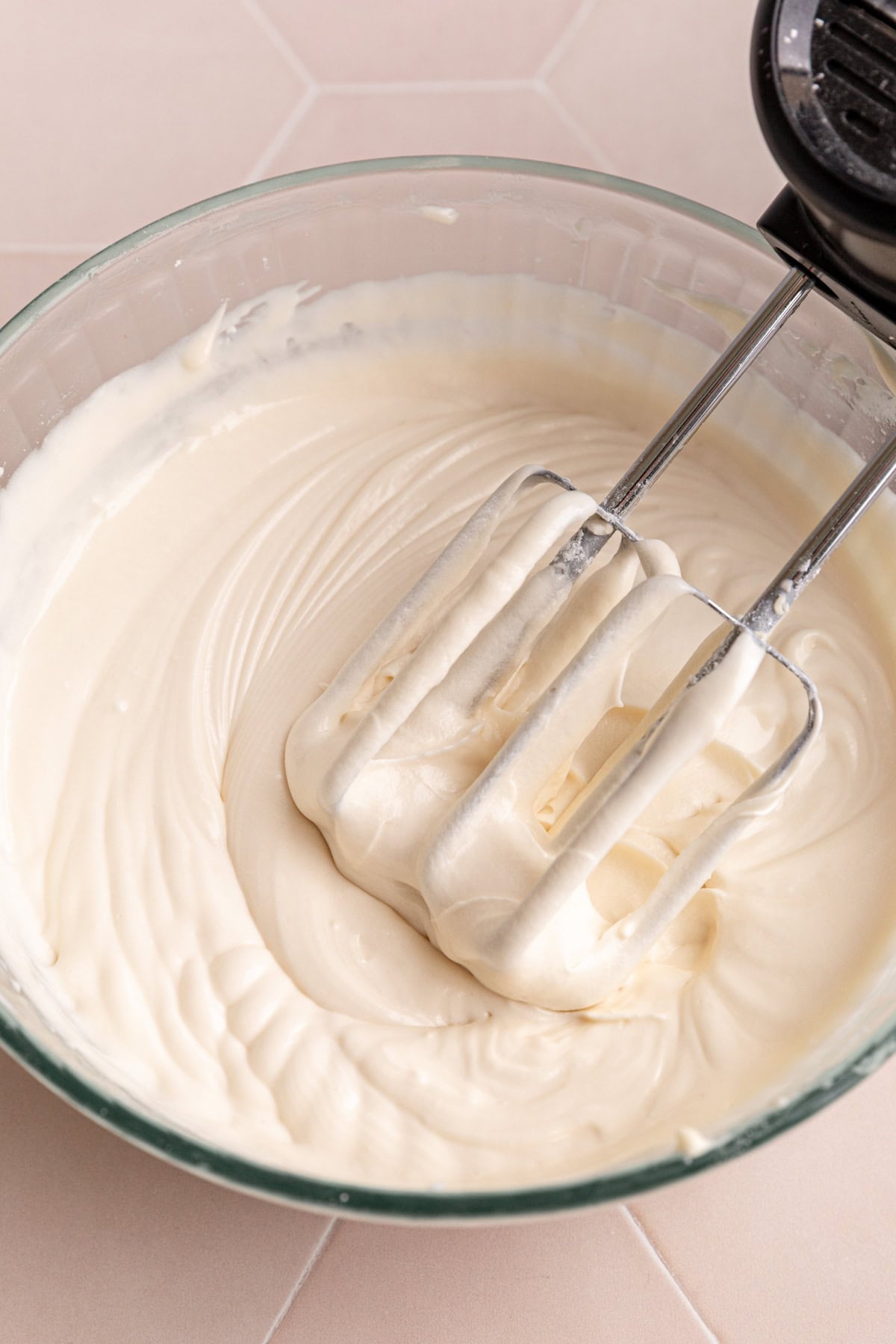 A bowl of Vegan Cream Cheese Frosting, with the beaters still in the bowl.