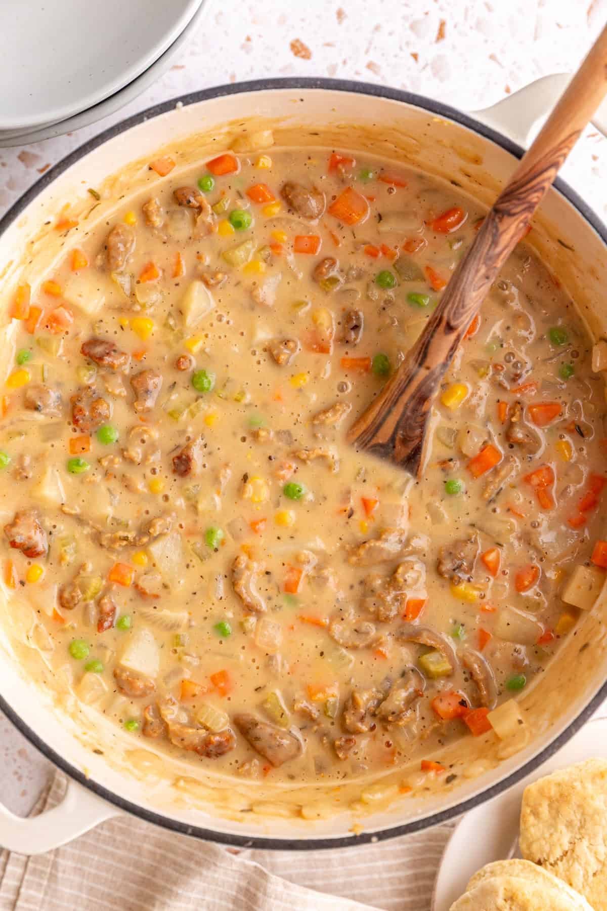 A pot of freshly cooked vegan pot pie soup, with a serving spoon.