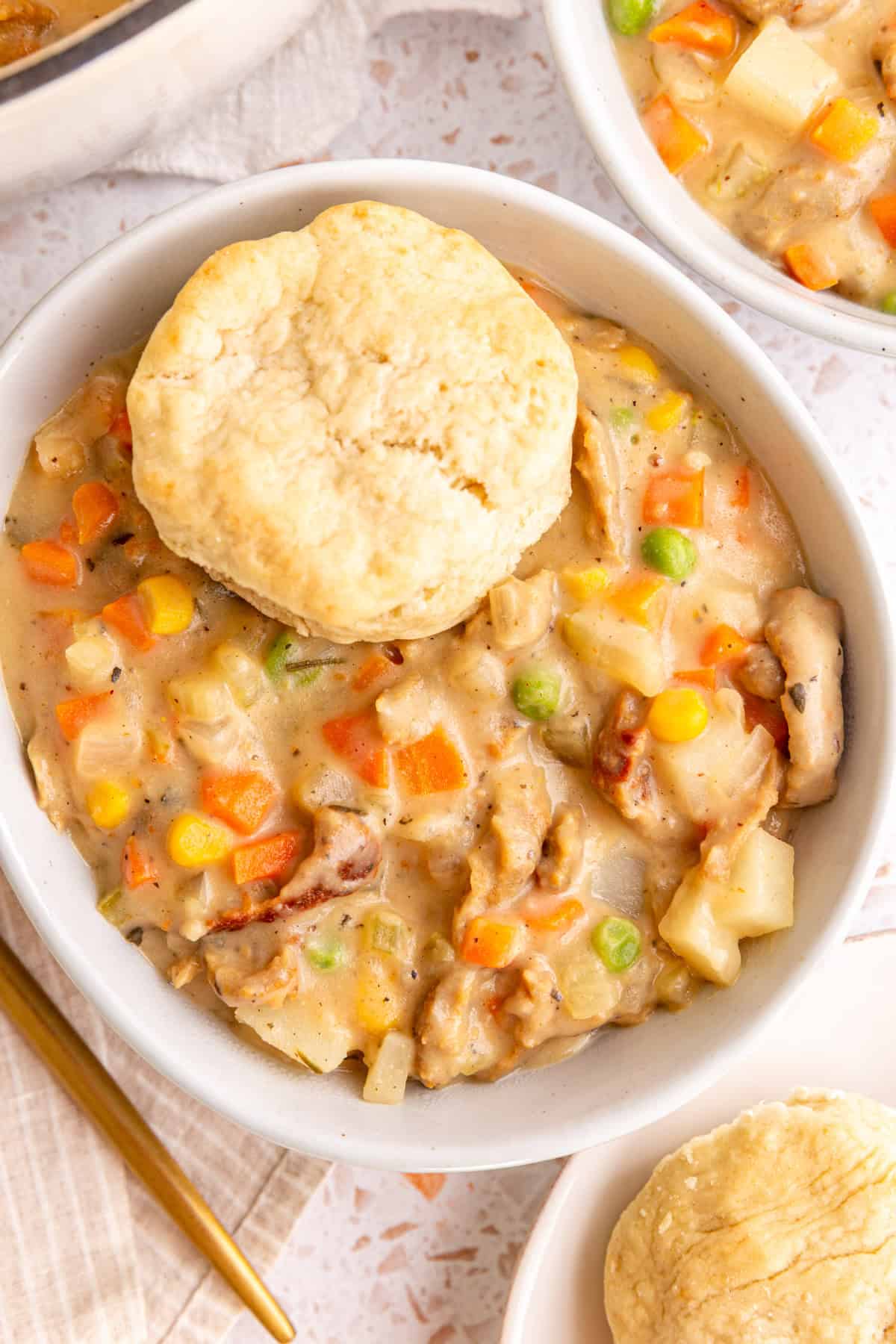 A bowl of vegan pot pie soup, with a biscuit on top.