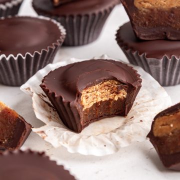 A bite taken out of a Vegan Reeses Caramel Big Cup to show the caramel and peanut butter layers.