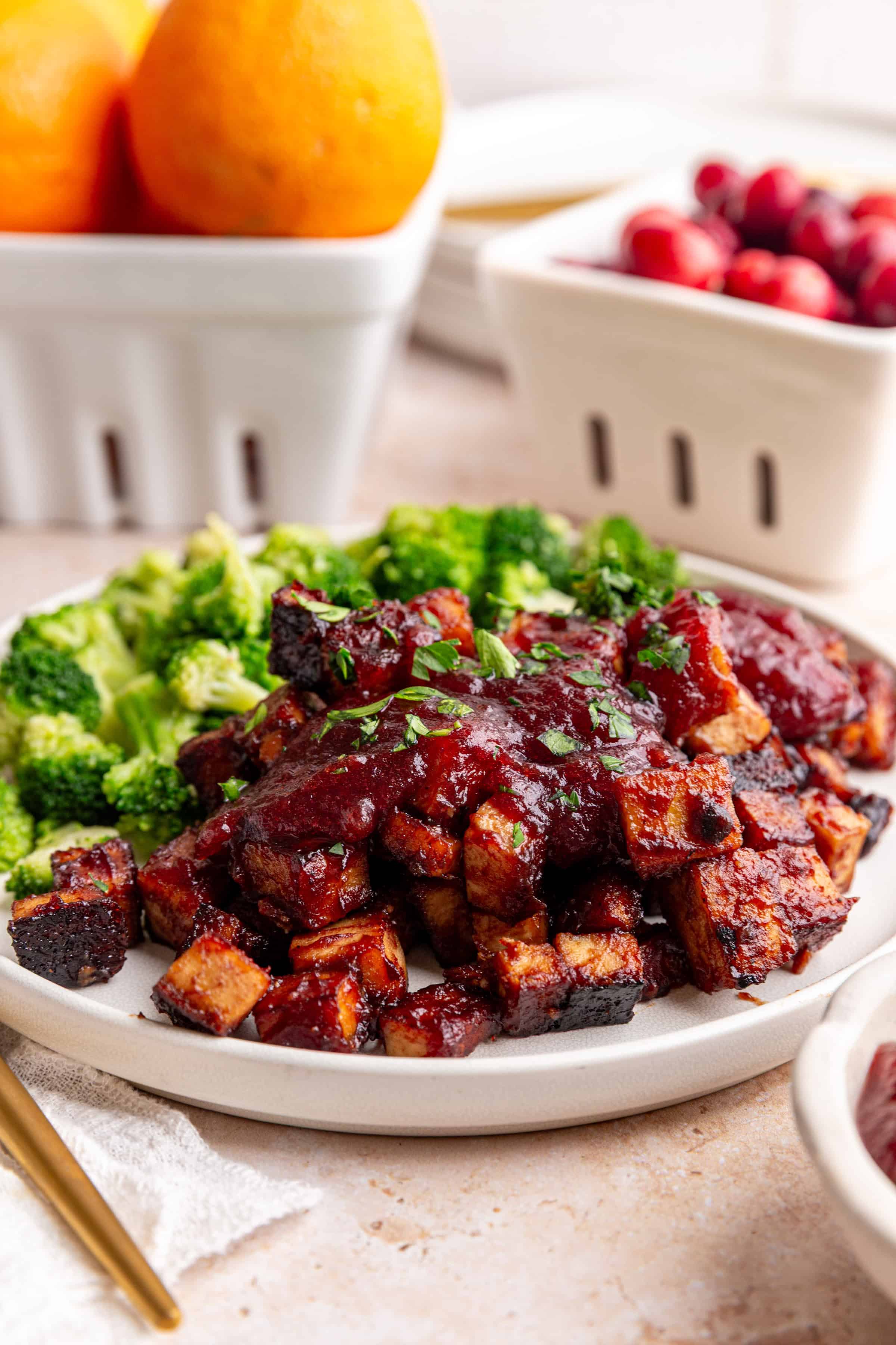 A plate of Cranberry Orange Tofu, topped with more sauce, and a side of broccoli.