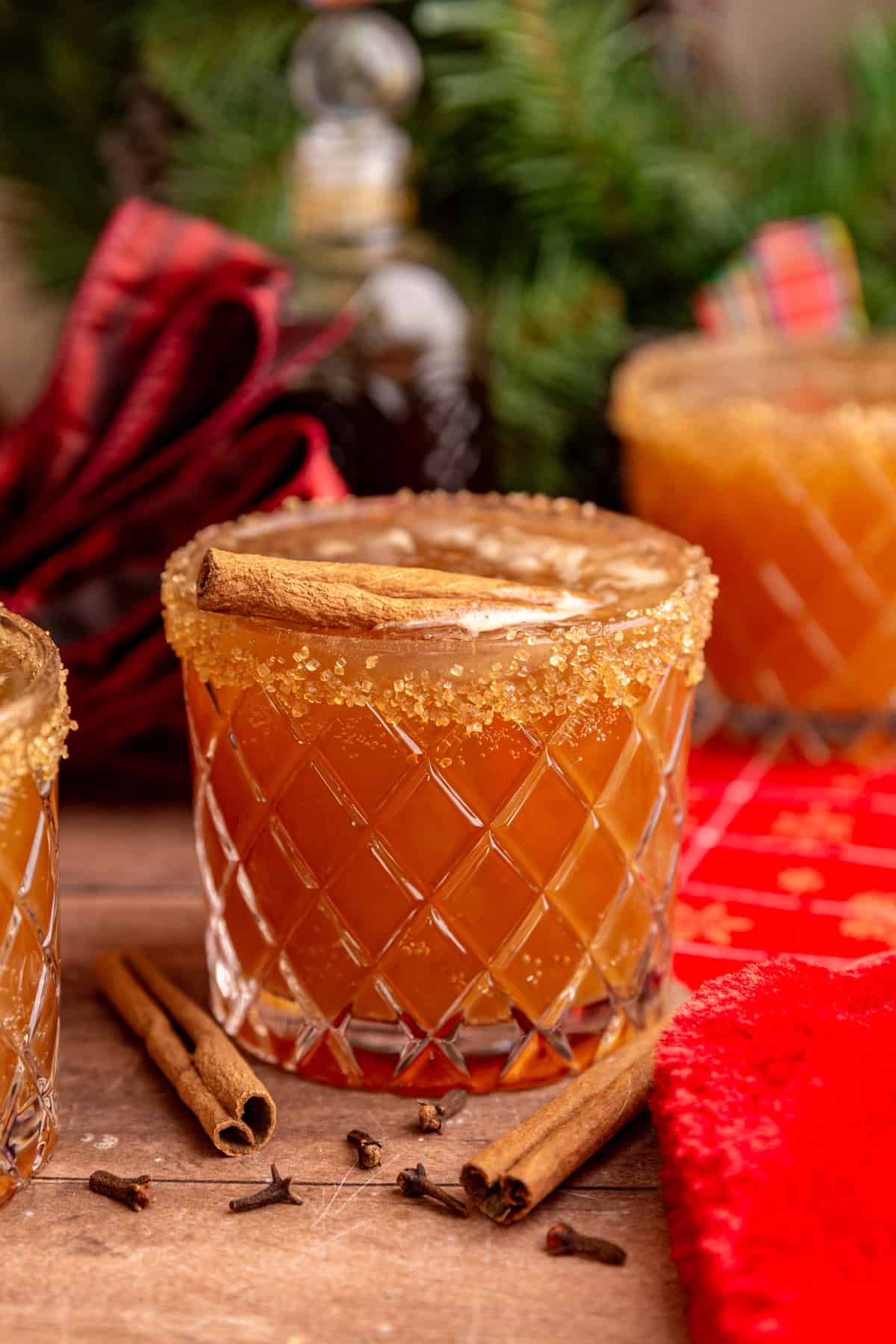 A gingerbread mocktail in a whiskey glass, rimmed with sugar and garnished with a cinnamon stick.