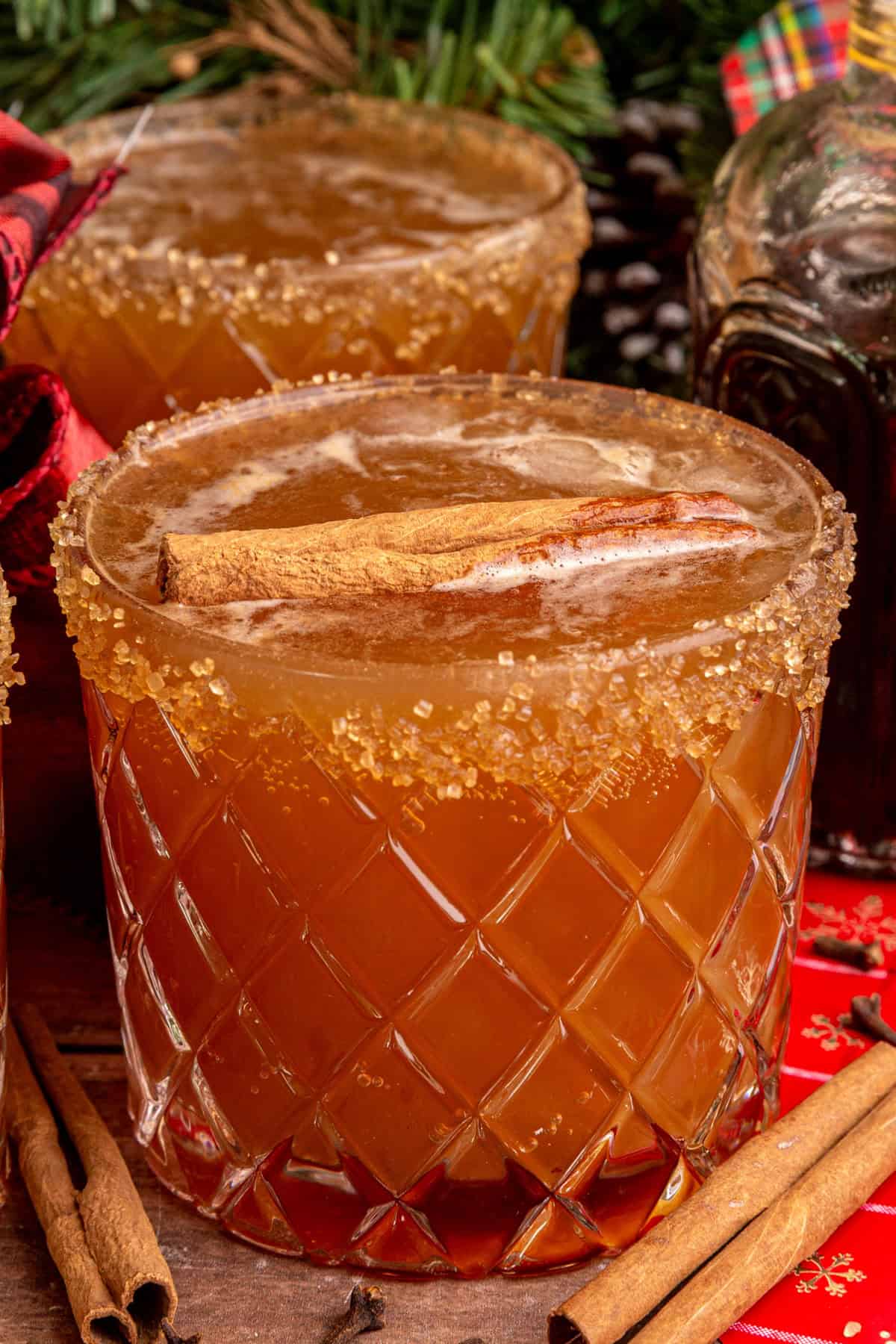 A gingerbread mocktail in a whiskey glass, rimmed with sugar and garnished with a cinnamon stick.