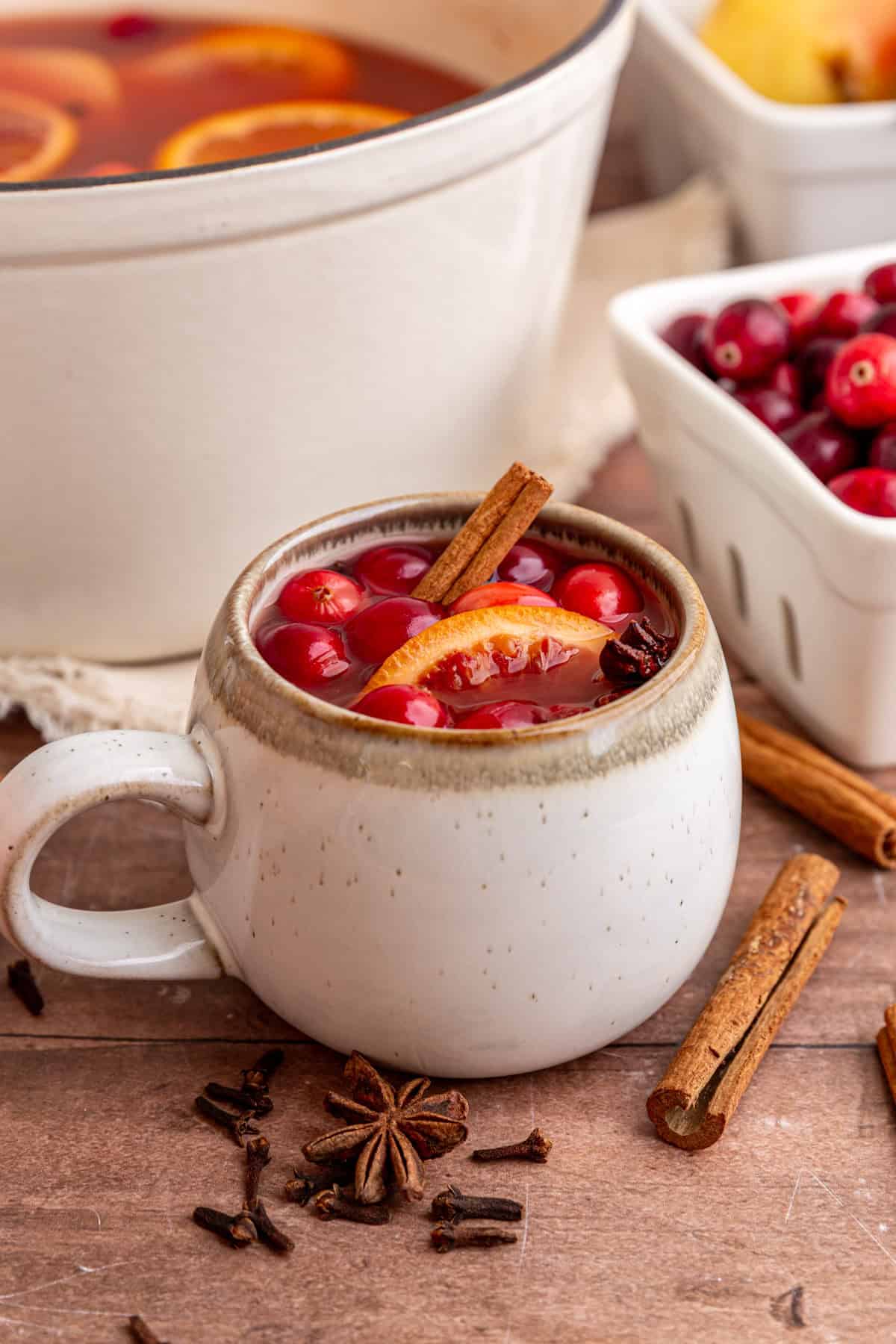 A mug of non alcoholic mulled wine, next to the pot.