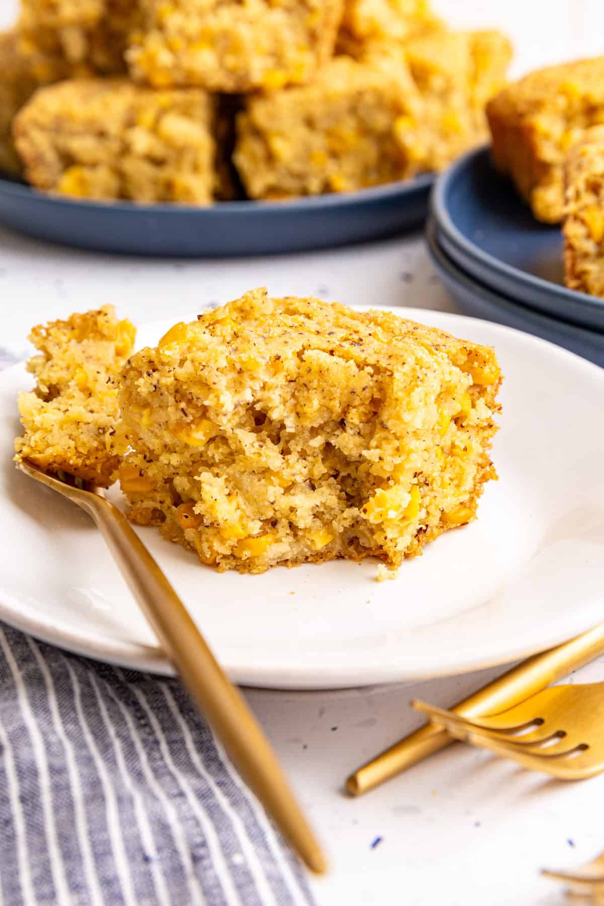A plate with a serving of vegan cornbread casserole, and a fork with a bite taken out of it.