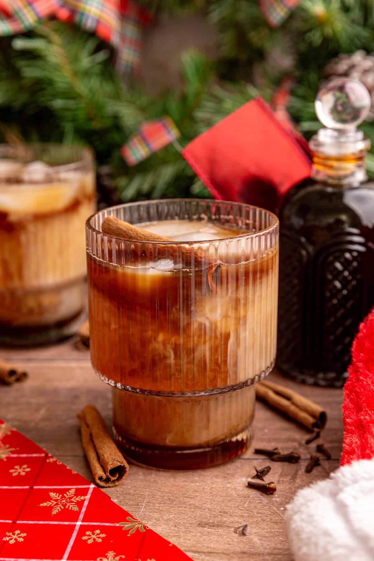 An iced vegan gingerbread latte garnished with a cinnamon stick.